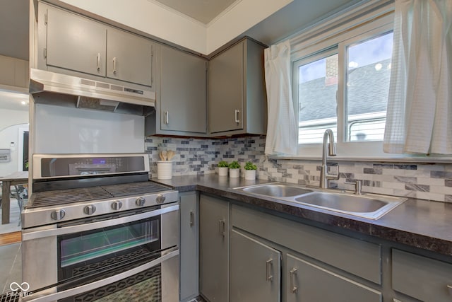 kitchen featuring stainless steel range, tasteful backsplash, gray cabinetry, and sink