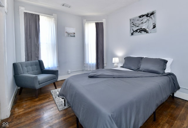 bedroom with dark hardwood / wood-style flooring and multiple windows