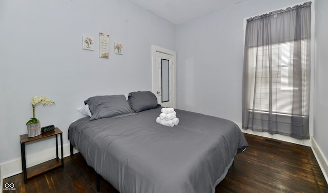 bedroom with multiple windows and dark wood-type flooring