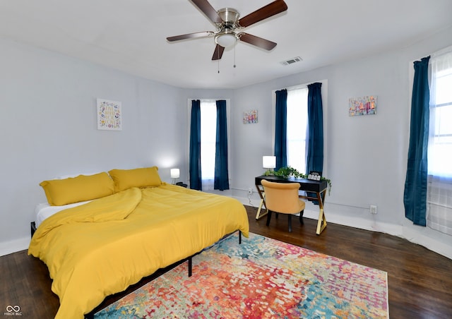 bedroom featuring multiple windows, dark wood-type flooring, and ceiling fan