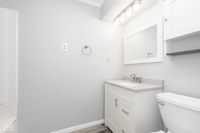 bathroom featuring crown molding, hardwood / wood-style flooring, vanity, and toilet