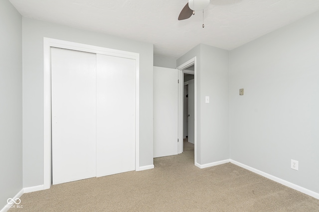 unfurnished bedroom with ceiling fan, a closet, and light carpet