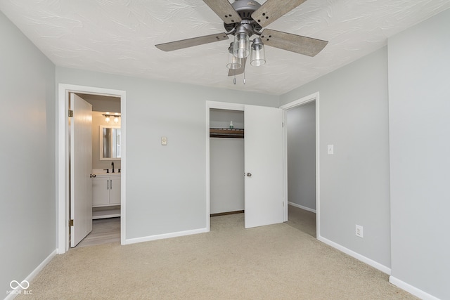 unfurnished bedroom featuring ceiling fan, connected bathroom, sink, a closet, and light colored carpet