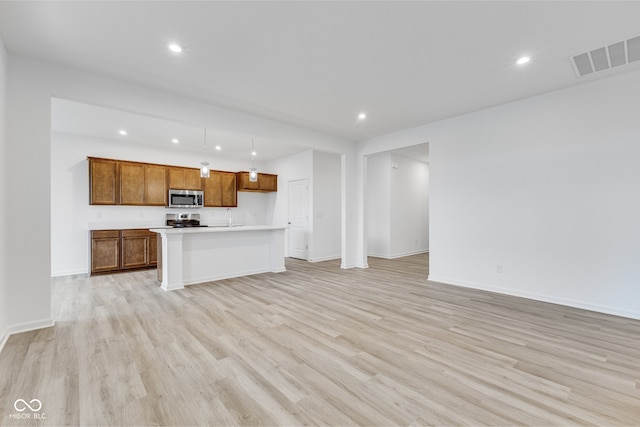 unfurnished living room featuring sink and light hardwood / wood-style flooring