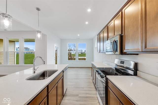 kitchen with hanging light fixtures, sink, light hardwood / wood-style floors, and appliances with stainless steel finishes