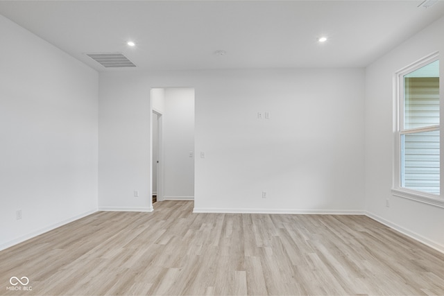 empty room with a wealth of natural light and light hardwood / wood-style floors