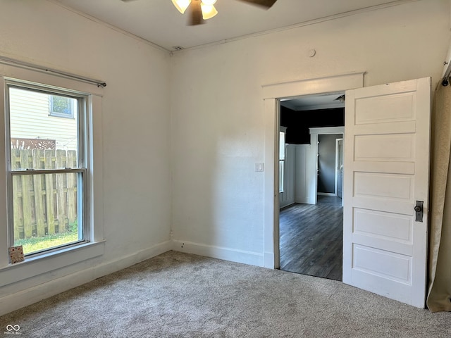 unfurnished room featuring dark carpet, ceiling fan, and crown molding