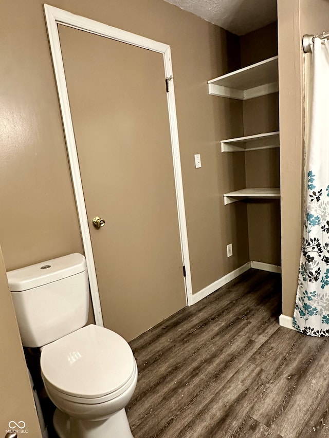 bathroom with hardwood / wood-style floors, toilet, and a textured ceiling