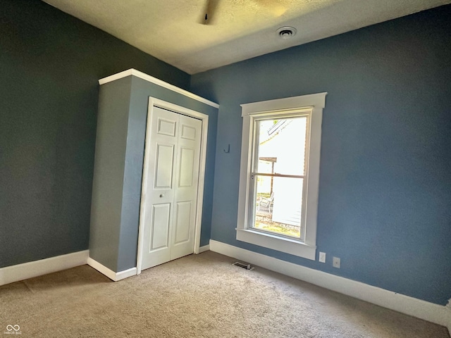 unfurnished bedroom featuring a closet, carpet, and a textured ceiling