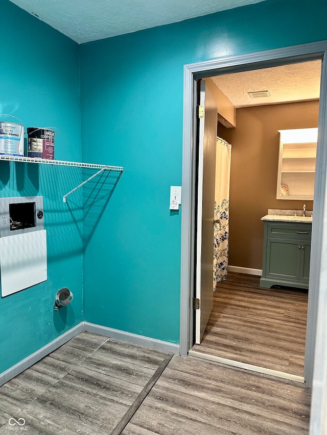 laundry room with sink, a textured ceiling, and light wood-type flooring