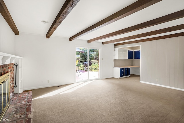 unfurnished living room featuring beamed ceiling, a brick fireplace, and dark carpet