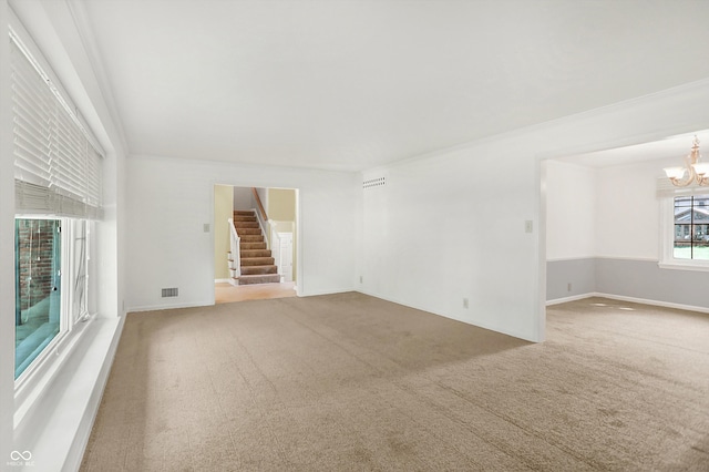 unfurnished living room featuring crown molding, an inviting chandelier, and carpet floors