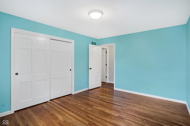 unfurnished bedroom featuring dark wood-type flooring and a closet