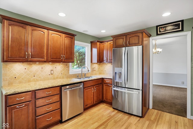 kitchen with a chandelier, light hardwood / wood-style flooring, sink, light stone countertops, and appliances with stainless steel finishes