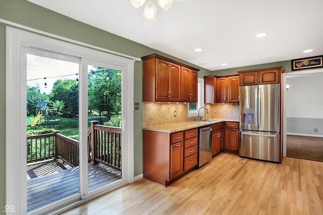 kitchen with light stone counters, light wood-type flooring, sink, and appliances with stainless steel finishes