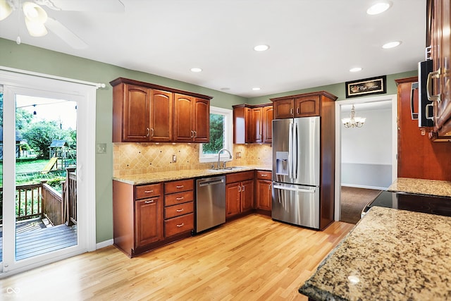 kitchen with ceiling fan with notable chandelier, tasteful backsplash, stainless steel appliances, sink, and light wood-type flooring