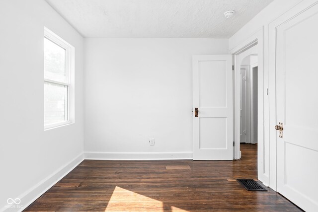 unfurnished room with a textured ceiling and dark hardwood / wood-style flooring