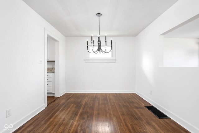 unfurnished dining area with a chandelier and dark hardwood / wood-style floors