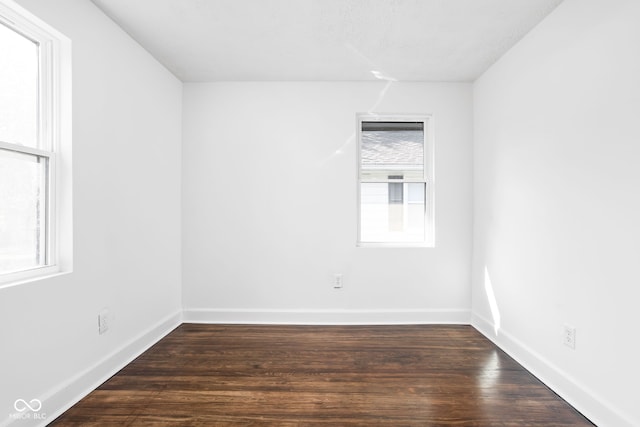 empty room featuring dark wood-type flooring and plenty of natural light