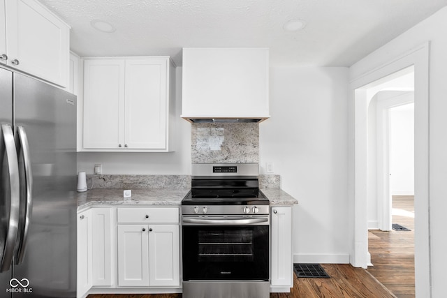 kitchen with light stone countertops, white cabinetry, stainless steel appliances, and dark hardwood / wood-style flooring