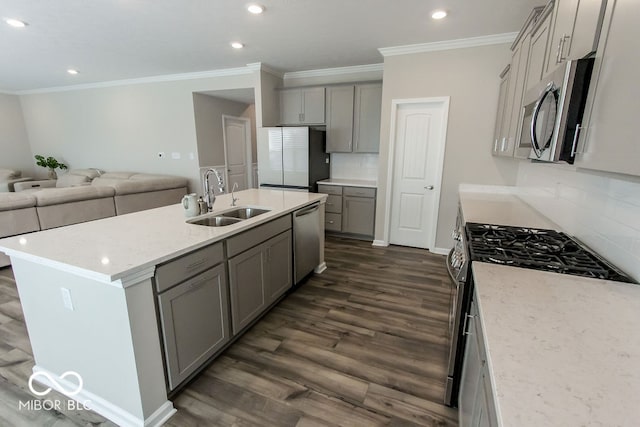 kitchen with appliances with stainless steel finishes, dark hardwood / wood-style flooring, sink, gray cabinets, and an island with sink