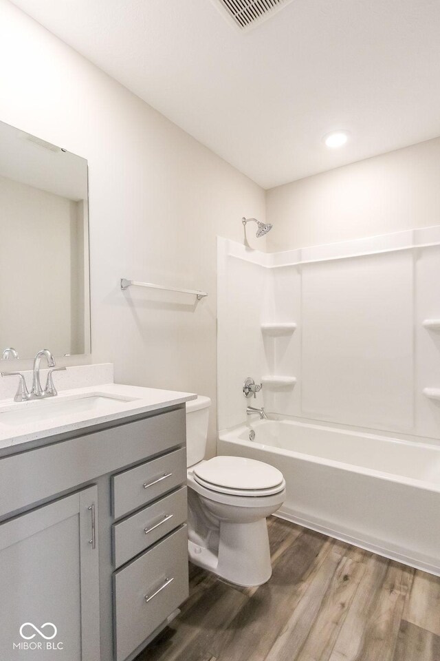 full bathroom featuring vanity, toilet,  shower combination, and hardwood / wood-style flooring