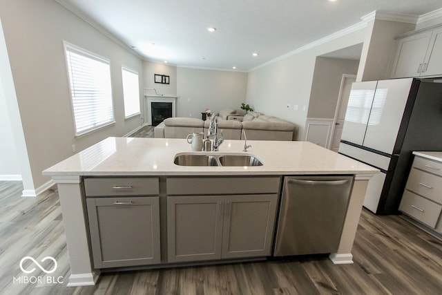 kitchen featuring gray cabinetry, an island with sink, stainless steel dishwasher, sink, and white refrigerator