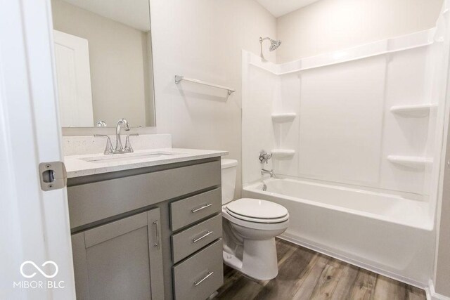 full bathroom featuring hardwood / wood-style floors, toilet, bathing tub / shower combination, and vanity