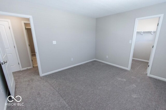 unfurnished bedroom with a closet, a spacious closet, and light colored carpet