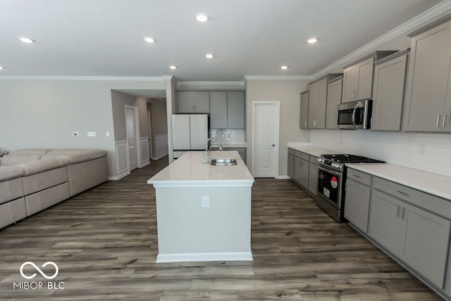 kitchen with appliances with stainless steel finishes, sink, gray cabinets, dark hardwood / wood-style floors, and an island with sink