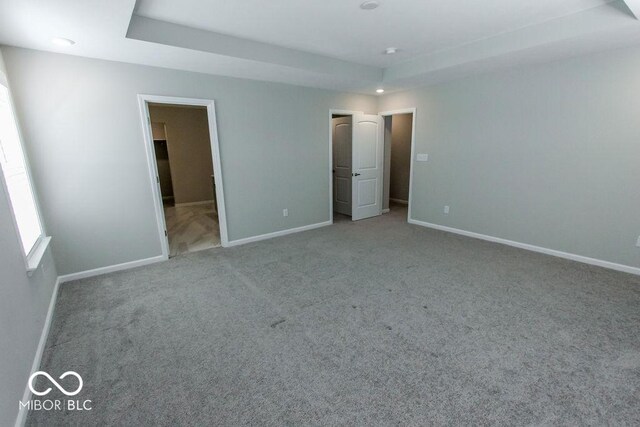 unfurnished bedroom featuring light carpet and a tray ceiling