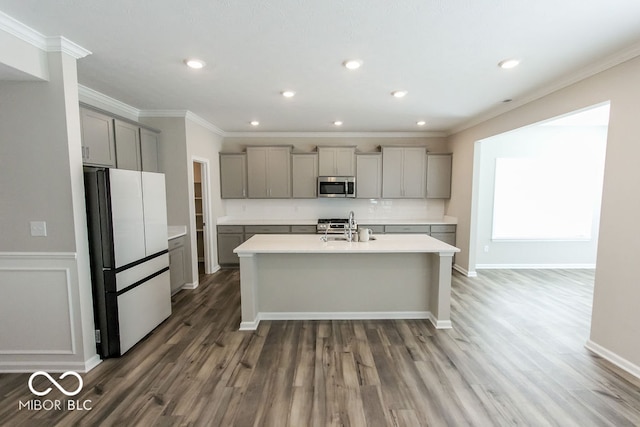 kitchen featuring white fridge, sink, dark hardwood / wood-style floors, a center island with sink, and gray cabinetry