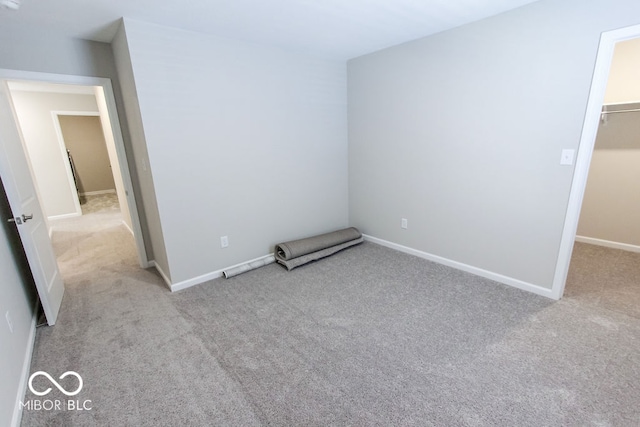 unfurnished bedroom featuring a walk in closet, a closet, and light carpet