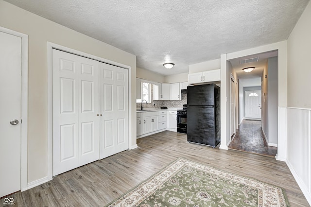 120 Hugo St, Indianapolis, IN 46229 - kitchen featuring light wood-type flooring, visible vents, black appliances, a sink, and white cabinets