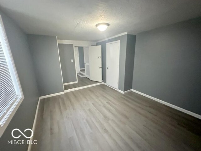 unfurnished bedroom featuring a textured ceiling, a closet, and hardwood / wood-style flooring