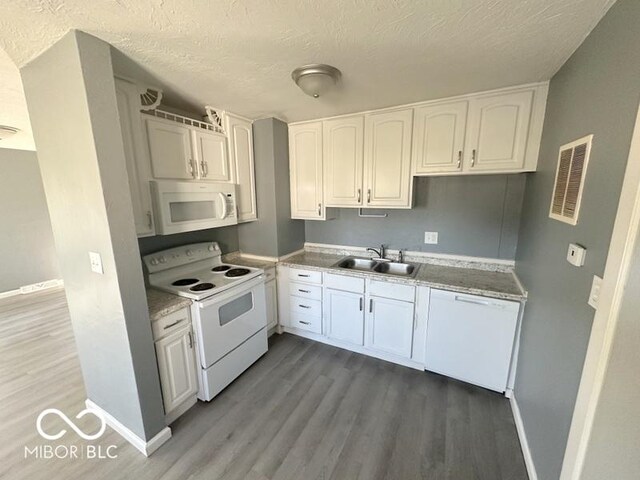 kitchen featuring white appliances, a textured ceiling, sink, hardwood / wood-style flooring, and white cabinets