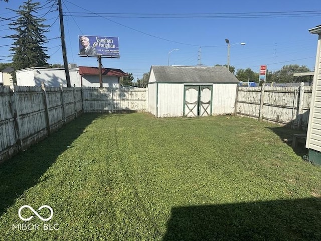 view of yard featuring an outbuilding, a fenced backyard, and a shed