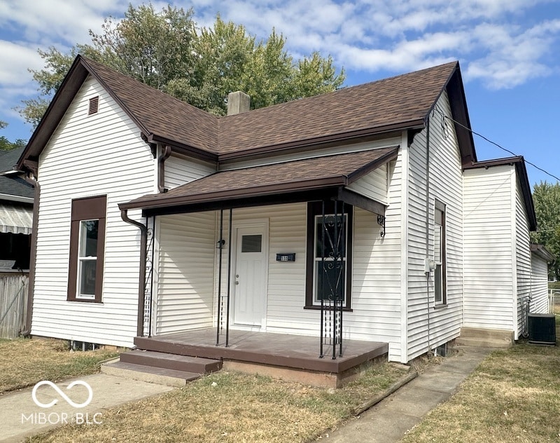 view of front of home featuring cooling unit, a porch, and a front lawn