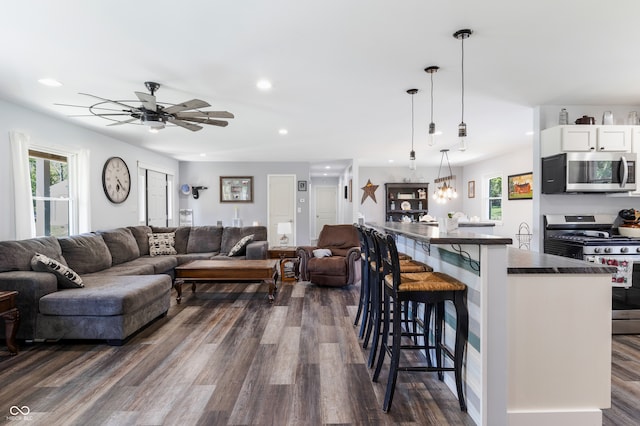 living room with dark wood-type flooring and ceiling fan