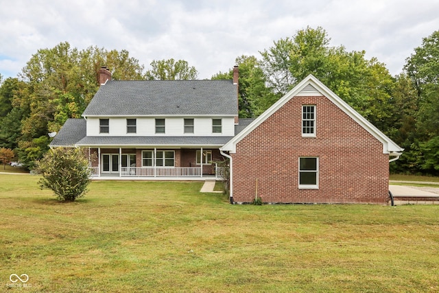 rear view of property featuring covered porch and a yard