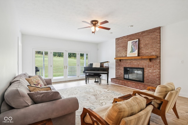 living room featuring light hardwood / wood-style flooring, ceiling fan, and a fireplace