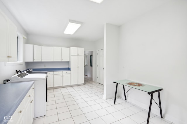 kitchen featuring white cabinets, light tile patterned floors, and washer / dryer