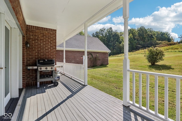 wooden terrace featuring a lawn and a grill