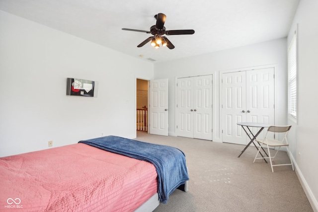 bedroom with ceiling fan, two closets, and carpet