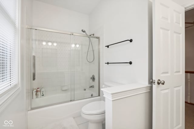 bathroom featuring combined bath / shower with glass door, tile patterned flooring, and toilet