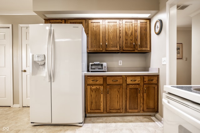 kitchen featuring ornamental molding, white refrigerator with ice dispenser, and light tile patterned floors