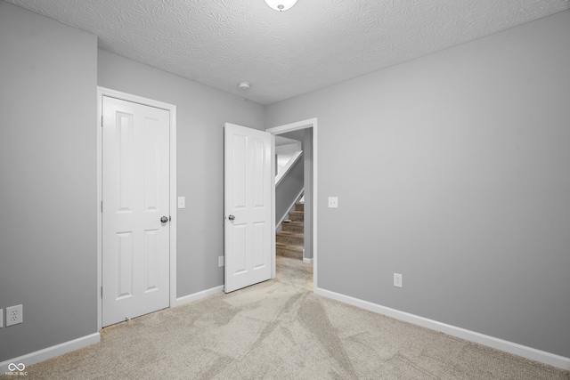 unfurnished bedroom featuring light carpet, a textured ceiling, and a closet