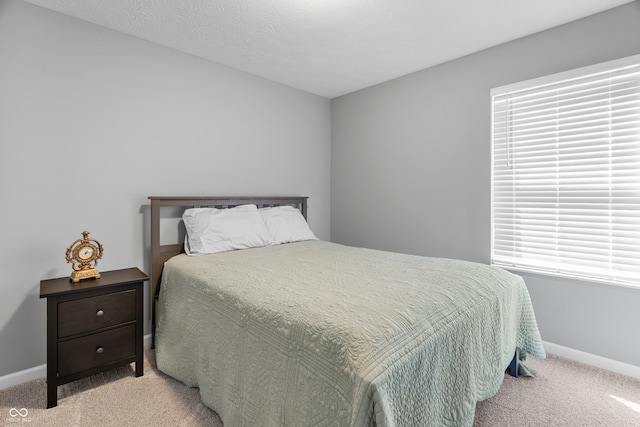 bedroom with light colored carpet and a textured ceiling