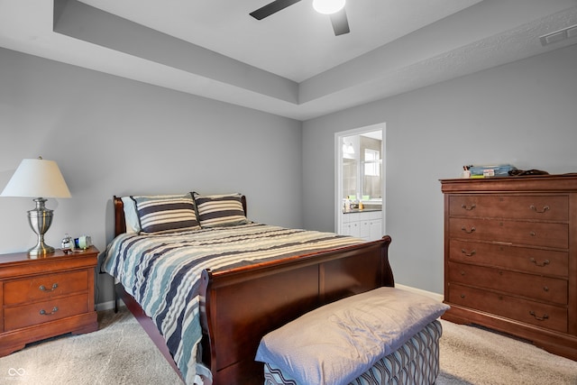 carpeted bedroom featuring ceiling fan, a tray ceiling, and connected bathroom