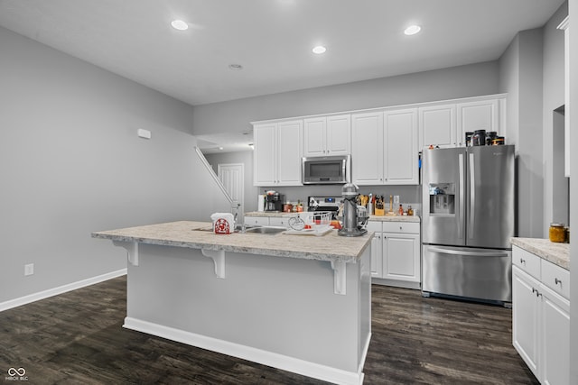 kitchen with white cabinets, a center island with sink, and stainless steel appliances